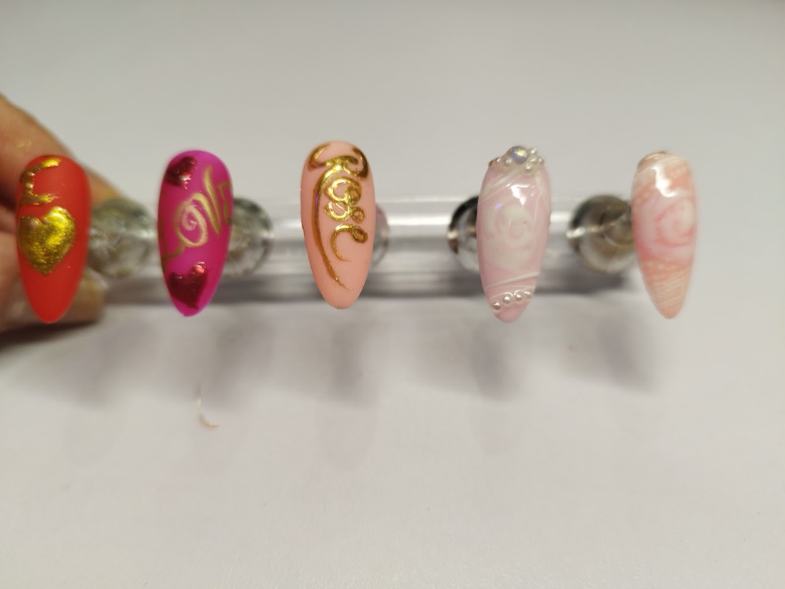 Hand-painted nail-art tips with gold lettering, hearts and pearl detail