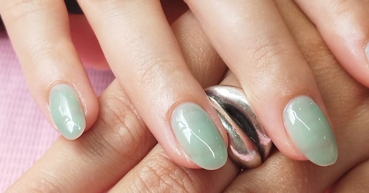 Close-up of sage-green ombre gel nails with a chrome accent